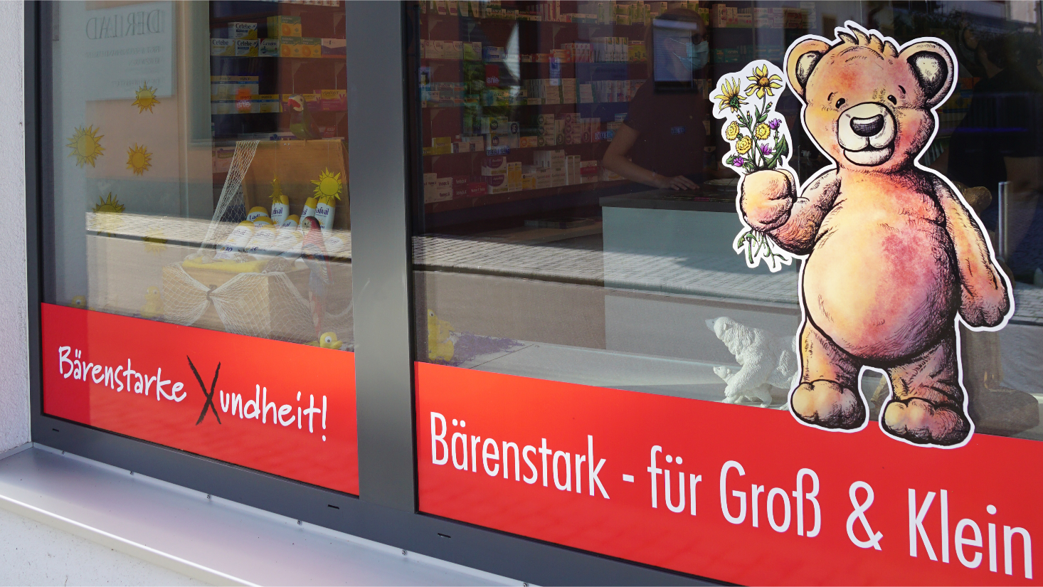 Schaufenster der Bärenapotheke Aichach mit dem aufgemalten Bären und dem Schriftzug ‚Bärenstark – für Groß und Klein‘
